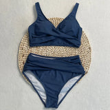 Maillot de bain deux pièces taille haute bleu marine, haut croisé et culotte drapée sur fond clair
