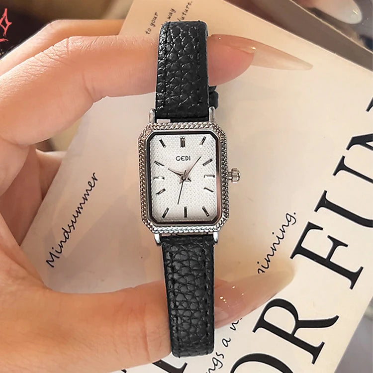 Montre femme vintage carrée GEDI, bracelet cuir noir, boîtier argenté, sur un livre ouvert