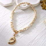 Détail du pendentif étoile de mer dorée et des coquillages sur le collier ras du cou