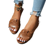 Gros plan sur les pieds de femme portant des sandales plates tressées marron sur un fond blanc
