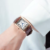 Montre carrée rétro femme bracelet cuir marron cadran blanc chiffres romains portée au poignet, détail manche chemise