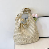 Sac de plage en paille tressée beige clair avec ruban en dentelle noué sur l'anse et fleur rose