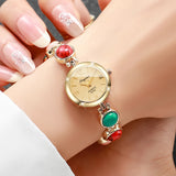 Montre femme élégante bracelet perles colorées vertes et rouges avec cadran doré portée au poignet