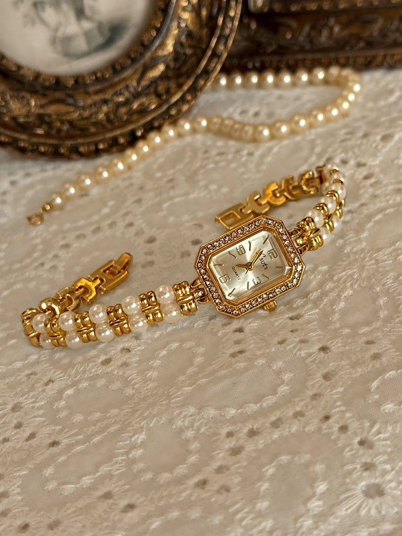 Montre élégante dorée pour femme avec perles et strass sur fond clair