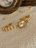 Montre élégante dorée pour femme avec perles et strass sur fond clair