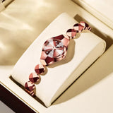 Montre femme bracelet doré rose et café sur présentoir, avec détails scintillants