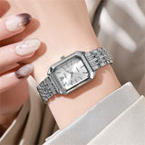 Montre carrée argentée avec cadran blanc portée au poignet d'une femme, clarté et raffinement.