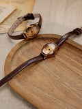 Montre vintage bracelet cuir marron posée sur un plateau en bois clair, style bohème