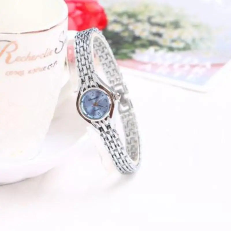 Montre bracelet femme argentée avec cadran bleu clair sur fond blanc et motifs floraux