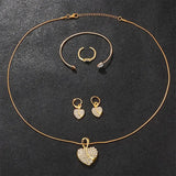 Vue d'ensemble du set bijoux doré femme avec montre, collier, boucles d'oreilles et bracelet sur fond sombre