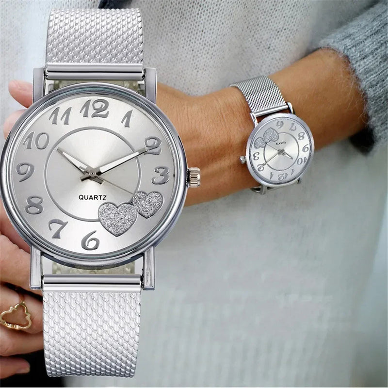 Montre femme élégante argentée avec cœurs scintillants et bracelet maille milanaise portée au poignet