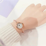 Gros plan d'une montre bracelet dorée avec cadran blanc à chiffres romains