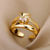 Bague ajustable dorée avec zircon central et anneau texturé sur fond beige