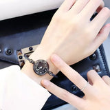 Montre bracelet argentée avec cadran noir à chiffres romains portée au poignet