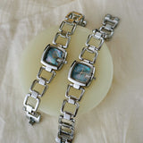 Paire de montres femme argentées, cadrans nacre bleus, bracelet acier, sur support