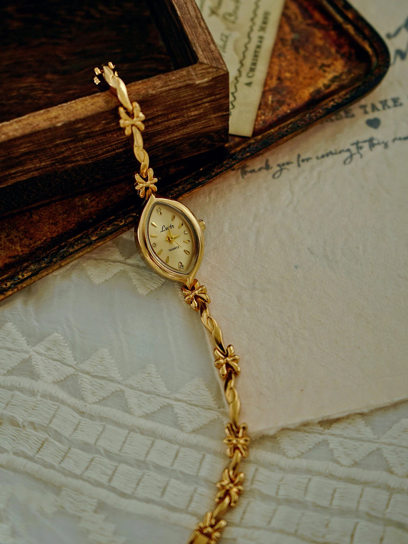 Montre dorée élégante, bracelet délicat motif floral sur fond texturé