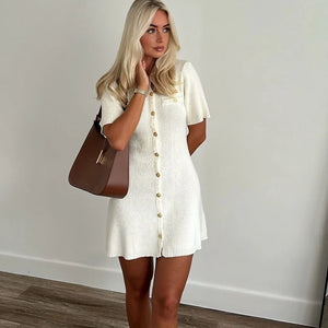 Femme portant une robe courte tricotée blanche avec boutons en métal, style épuré, automne.