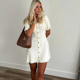 Femme portant une robe courte tricotée blanche avec boutons en métal, style épuré, automne.