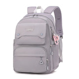 Sac à dos collège gris en nylon à grande capacité avec bretelles réglables et poches de rangement.