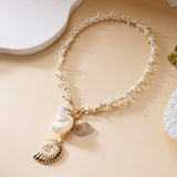 Collier ras du cou avec petites étoiles de mer blanches et coquillage doré sur fond beige
