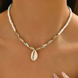 Collier ras-du-cou perles coquillages naturelles et pendentif étoile de mer dorée sur fond clair