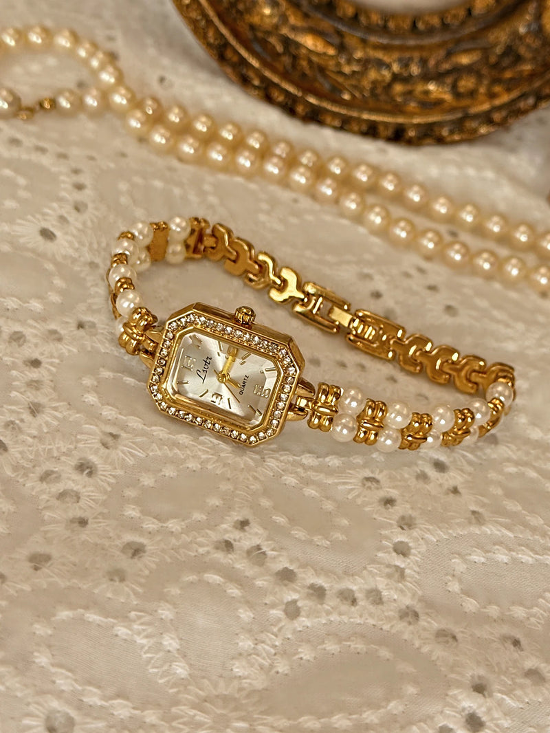 Montre femme dorée avec cadran rectangulaire et bracelet double rang de perles sur dentelle