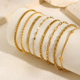 Divers styles de bracelets chaînes dorés portés ensemble sur un poignet