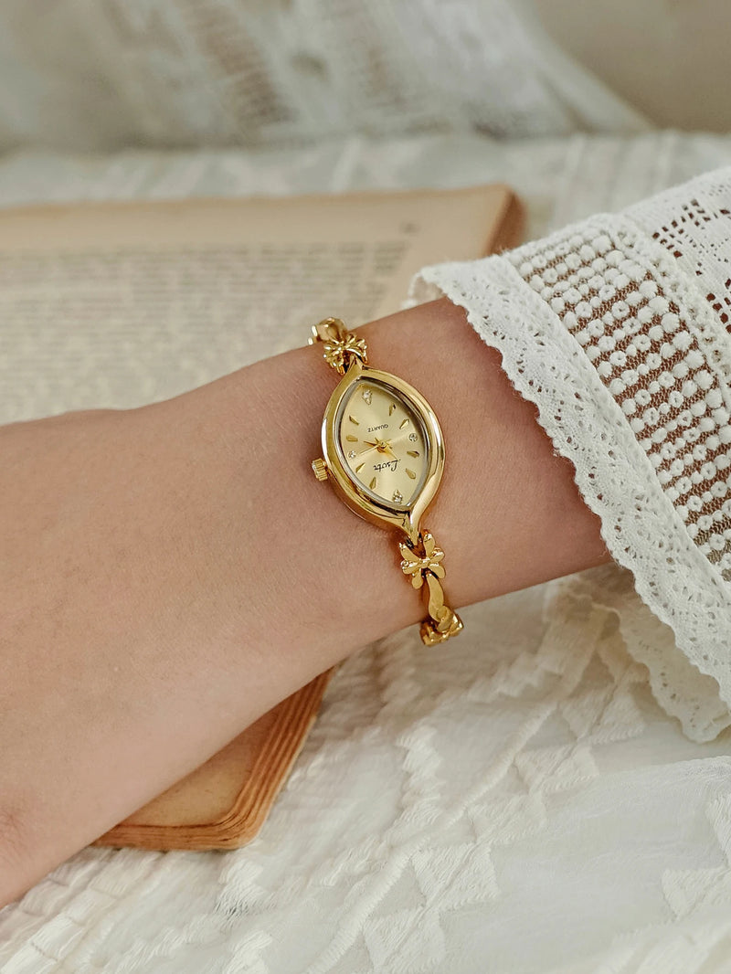 Montre dorée femme, petit cadran ovale, bracelet fin sur un poignet féminin