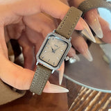 Montre femme vintage carrée GEDI, bracelet cuir noir, boîtier doré, portée au poignet
