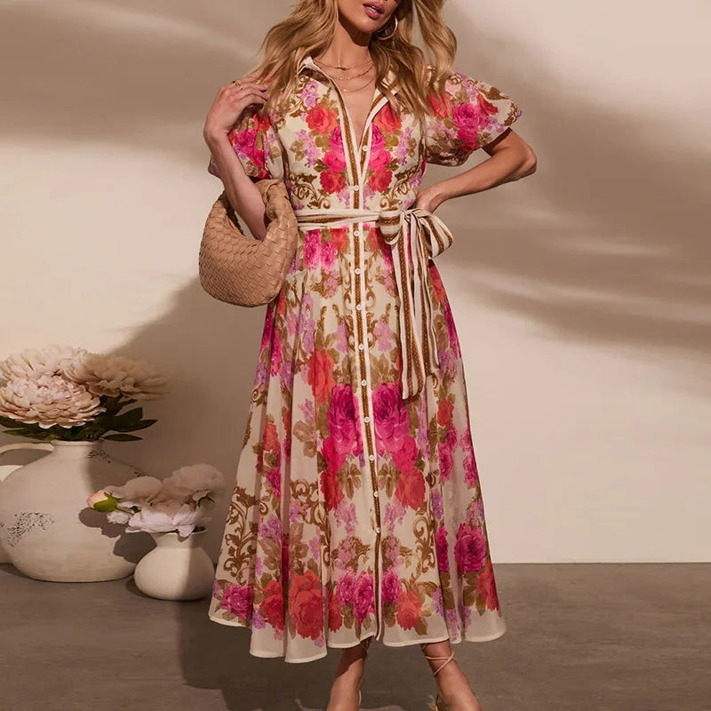 Femme portant une robe bohème longue fleurie avec ceinture nouée, col chemise et manches courtes bouffantes