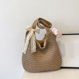 Sac cabas en paille tressée marron avec ruban en dentelle beige noué sur l'anse