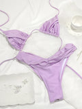 Ensemble bikini triangle plissé lilas posé sur une fourrure blanche avec bijoux