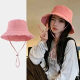Jeune femme portant un chapeau bob rose effiloché avec cordon, look décontracté