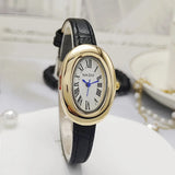 Montre ovale vintage avec bracelet en cuir noir et cadran doré, posée sur un support