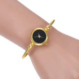 Montre bracelet dorée avec cadran noir portée au poignet