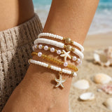 Femme sur la plage présentant un lot de bracelets fantaisie blancs et dorés avec motifs marins
