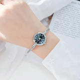 Montre bracelet argentée avec cadran noir à chiffres romains portée par une femme