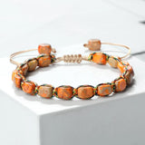 Bracelet bohème perles pierre impériale orange tressé main sur fond blanc