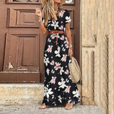 Femme portant une robe longue fleurie noire avec ceinture marron et chapeau de paille