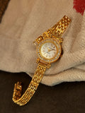 Montre quartz dorée avec cadran nacre et strass posée sur un tissu beige clair