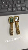 Deux montres femme carrées, une verte dorée et une blanche dorée, posées sur un clavier d'ordinateur, affichant le logo YIKAZE WATCH