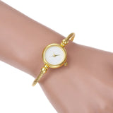 Montre bracelet dorée avec cadran blanc portée au poignet