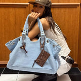 Femme portant un grand sac fourre-tout bleu clair style Y2K avec détails métalliques