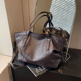 Sac cabas femme marron foncé en cuir PU souple posé sur une commode devant un miroir