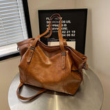 Sac cabas femme marron clair grand format en cuir PU souple posé sur une table en métal