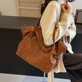 Femme portant un sac cabas marron clair en cuir PU souple, vue de côté, dans un intérieur moderne