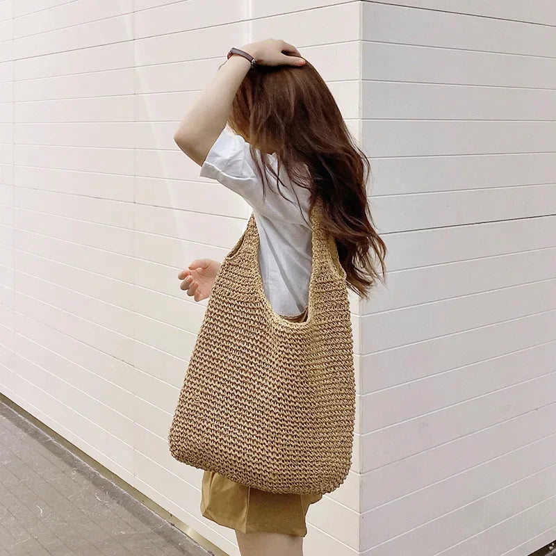 Femme portant le sac de plage tressé beige sur l'épaule, vue de dos