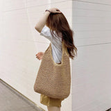 Femme portant le sac de plage tressé beige sur l'épaule, vue de dos