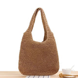 Sac de plage tressé marron posé sur une table en bois