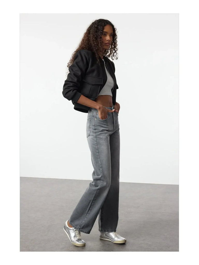 Femme portant un jean vintage taille haute évasé 100% coton avec un crop top et une veste noire.